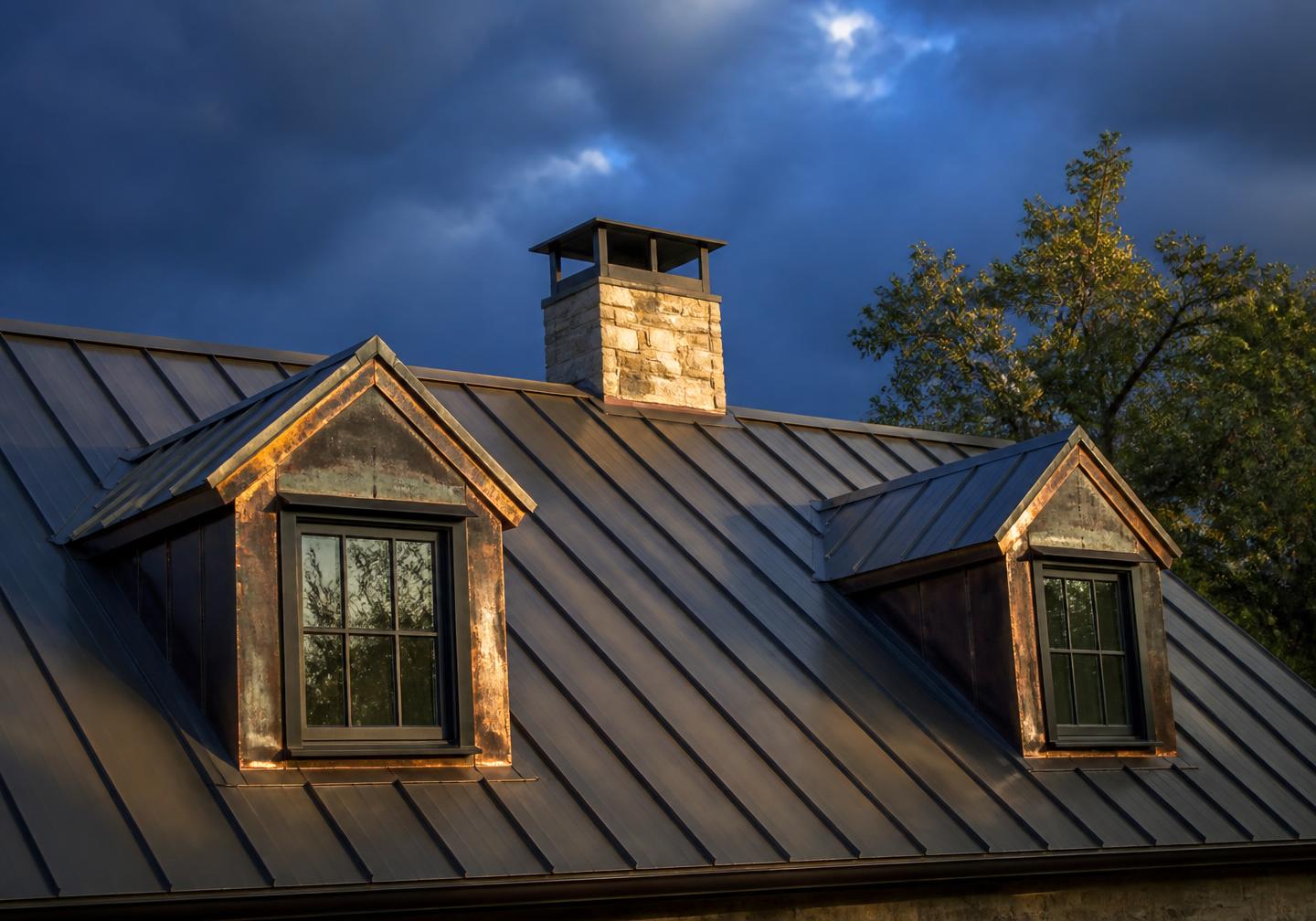 Standing seam metal roof with copper flashing under a storm-lit Texas sky